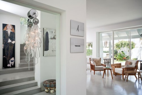 דרך מראה דגולה בכניסה לבית משתקפים ציורי שמן של דים יוז ושל שירה סגול. לצד המראה נתלו צמד תצלומי סיכות של בועז אהרונוביץ' . צילום: בועז לביא