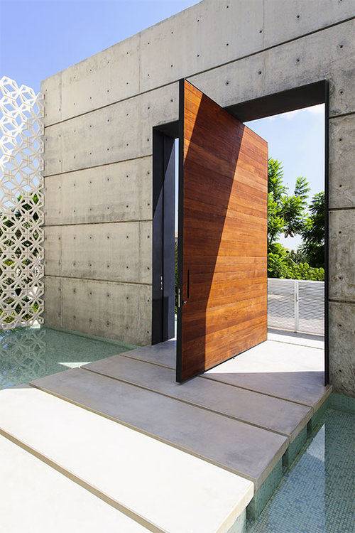 דלת עץ גדולה מובילה אל מבואה חיצונית. בית בסביון | צילום: מושי גיטליס