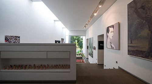 מבט מחלל הכניסה עד לחצר הבית. על קיר המסדרון ציור של איזבלה רוסליני של אלין אלג'ם (20 אלף ש״ח) וכפפות אגרוף של קרן שפילשר (2,000 ש״ח). מידע על העבודות אפשר למצוא באתר של בר גיל: kerenbargil.com | צילום: איתי סיקולסקי