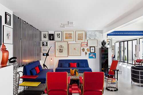 אוסף עבודות אמנות בסוגי מדיה שונים שמוטיב כף היד חוזר בהן רוכז מעל פינת הישיבה השניה בבית, שעוצבה בצבעי היסוד אדום, כחול וצהוב בהשראת כיסא איקוני בעיצוב האדריכל והמעצב ההולנדי גריט ריטוולד | צילום: בועז לביא