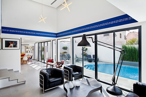 תקרה גבוהה במיוחד מעל פינת הישיבה השחורה נוצלה להצבת עבודת טקסט של דאגלאס גורדון החולשת על החלל כולו, וכוללת טקסט לבן בעברית שנכתב על סטריפ צבע כחול על פי הוראות מדויקות של האמן | צילום: בועז לביא