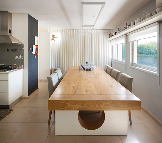 שולחן עץ מבוקע עם רגל ובה עיגול וגוף תאורה מינימליסטי תוכננו על ידי המעצבת | צילום: שי אפשטיין