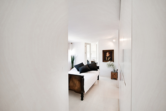 מבט אל הכניסה לחדר השינה. דלת גדולה מפרידה בינו לבין החלל המשותף. האהבה לאופנה ניכרת גם באמנות המעטרת את קירות הבית | צילום: איתי סיקולסקי