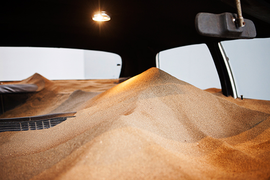 מכונית ישנה מדגם דודג', מלאה בחול המכסה את כל חלל הפנים שלה | באדיבות האמן אנדרֵס מרוקאן וינקלמן וגלריה Revolver