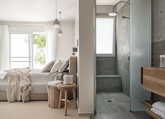 חדר השינה לא קונבנציונלי והוא מאוזן בעדינות בין חומרים קרים כמו אריחים דמויי בטון ומראה מינימליסטי בחלל המקלחון, ברצפה ועל הקירות, לבין חמימות של עץ טבעי, של טקסטיל ושל צמחייה | צילום: גלעד רדט 