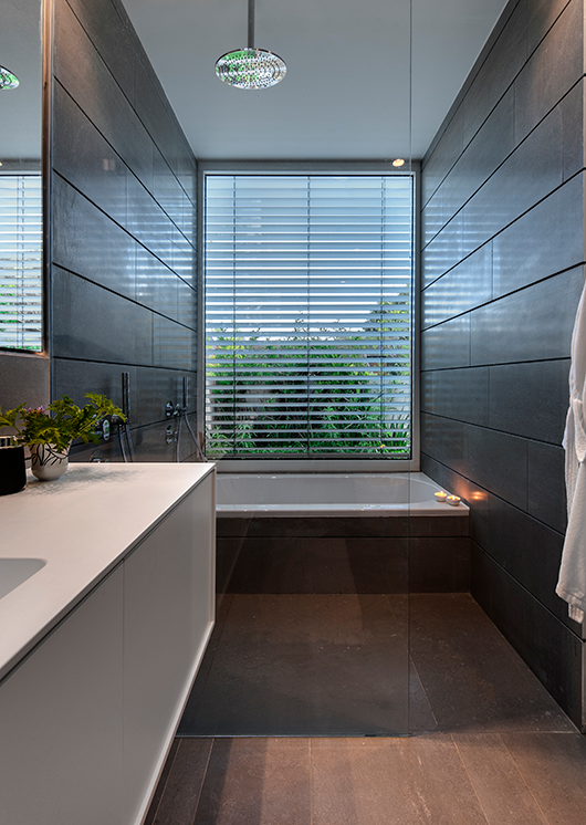 לוח זכוכית בגוון מעושן מחלק את חדר הרחצה לאזור רטוב ואזור יבש | צילום: עודד סמדר