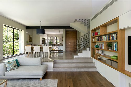 שלוש מדרגות מפרידות בין פינת האוכל לסלון. פרקט וריצוף אבן אפורה תוחמים את האזורים השונים | צילום: שירן כרמל