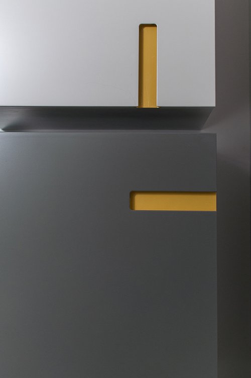 לשידות הנפרדות בגוני אפור בהיר וכהה ידיות שקועות הצבועות בחרדל. יחד הן מייצרות משחק ויזואלי מעניין עם השידה המרכזית בחדר | צילום: סיון אסקיו