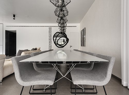 שולחן אלומיניום דק רגליים, שורת מנורות בעיצוב גיאומטרי ומסגרת מראה הנראית כשרבוט גרפי הופכים את פינת האוכל למרחב קליל ואוורירי | צילום: עודד סמדר