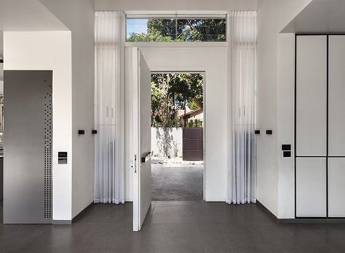 סקאלת הצבעים המונוכרומטית והמשחקים הגרפיים המאפיינים את הבית נרמזים כבר במבואת הכניסה | צילום: עודד סמדר