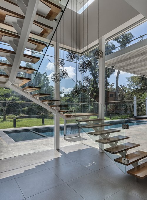 מעקה הזכוכית המלווה את גרם המדרגות האוורירי מאפשר חשיפה מקסימלית גם של אזור זה אל החצר האחורית הירוקה  | צילום: עודד סמדר