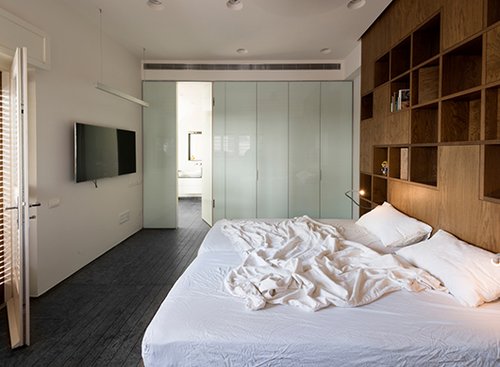 דירה בתל אביב: קיר עץ מודולרי המפריד בין חדר השינה לסלון, מורכב מקוביות עץ נשלפות  | צילום: גדעון לוין