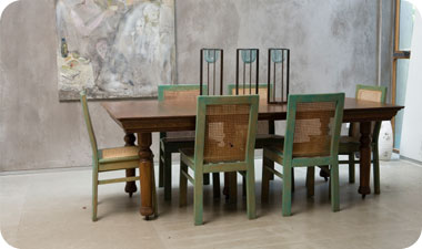 שולחן האוכל במרכז עשוי מעץ בן 130 שנה, ומסביבו שישה כיסאות עץ בשילוב קש